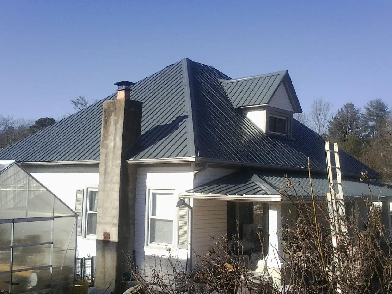 Dark blue standing seam metal roof on a white farmhouse with dormer — Slate & Tile Roof Repair by Roofing Brothers in Russiaville