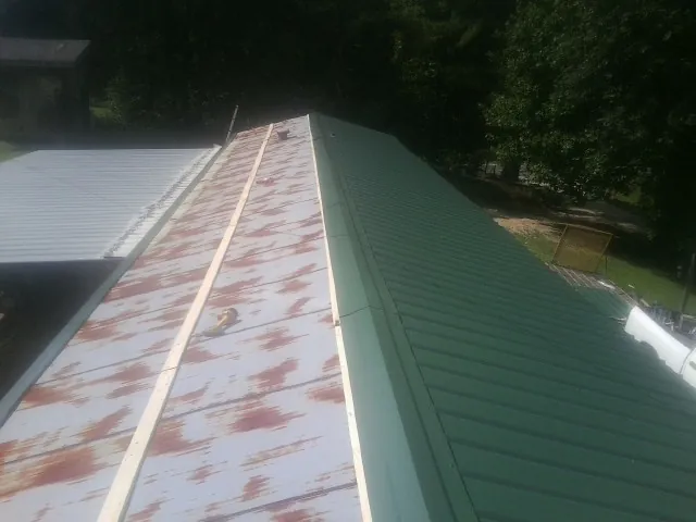 Old rusted panels beside newly installed green metal roofing — Wind Damage Roof Repair by Roofing Brothers in Russiaville