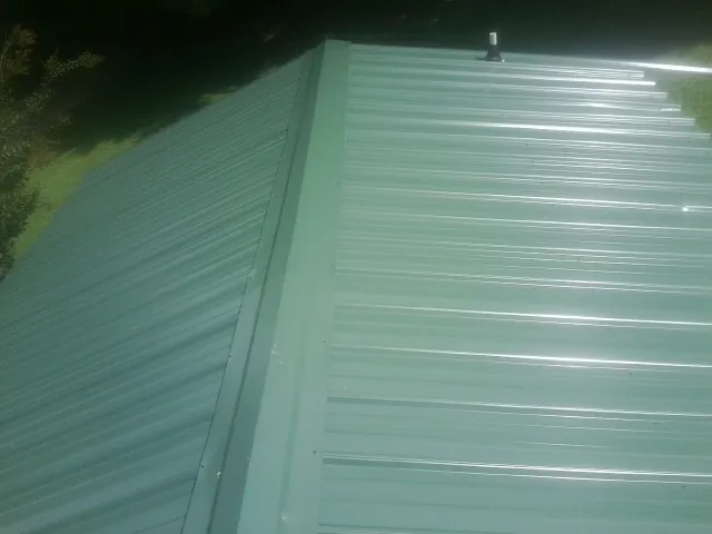 New green metal panels meeting at the ridge of a roof in Russiaville