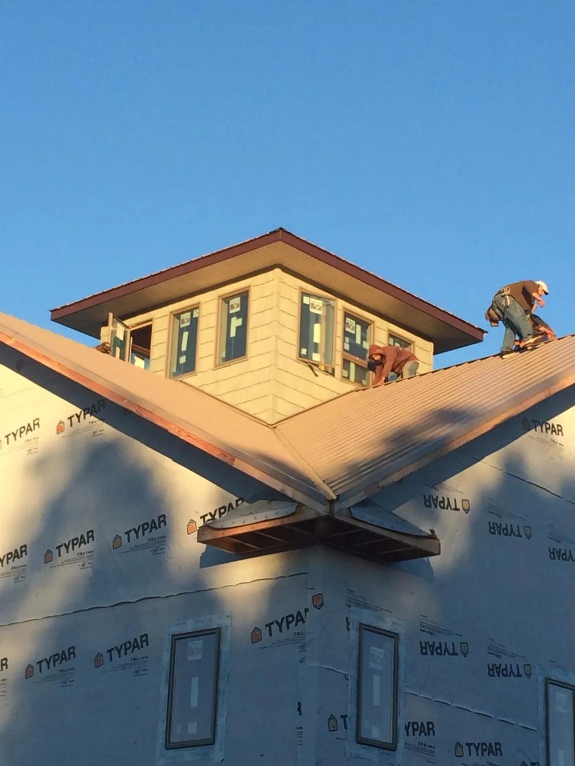 Roofers working around a rooftop cupola on a new metal roof at sunset — Roof Waterproofing in Russiaville by Roofing Brothers